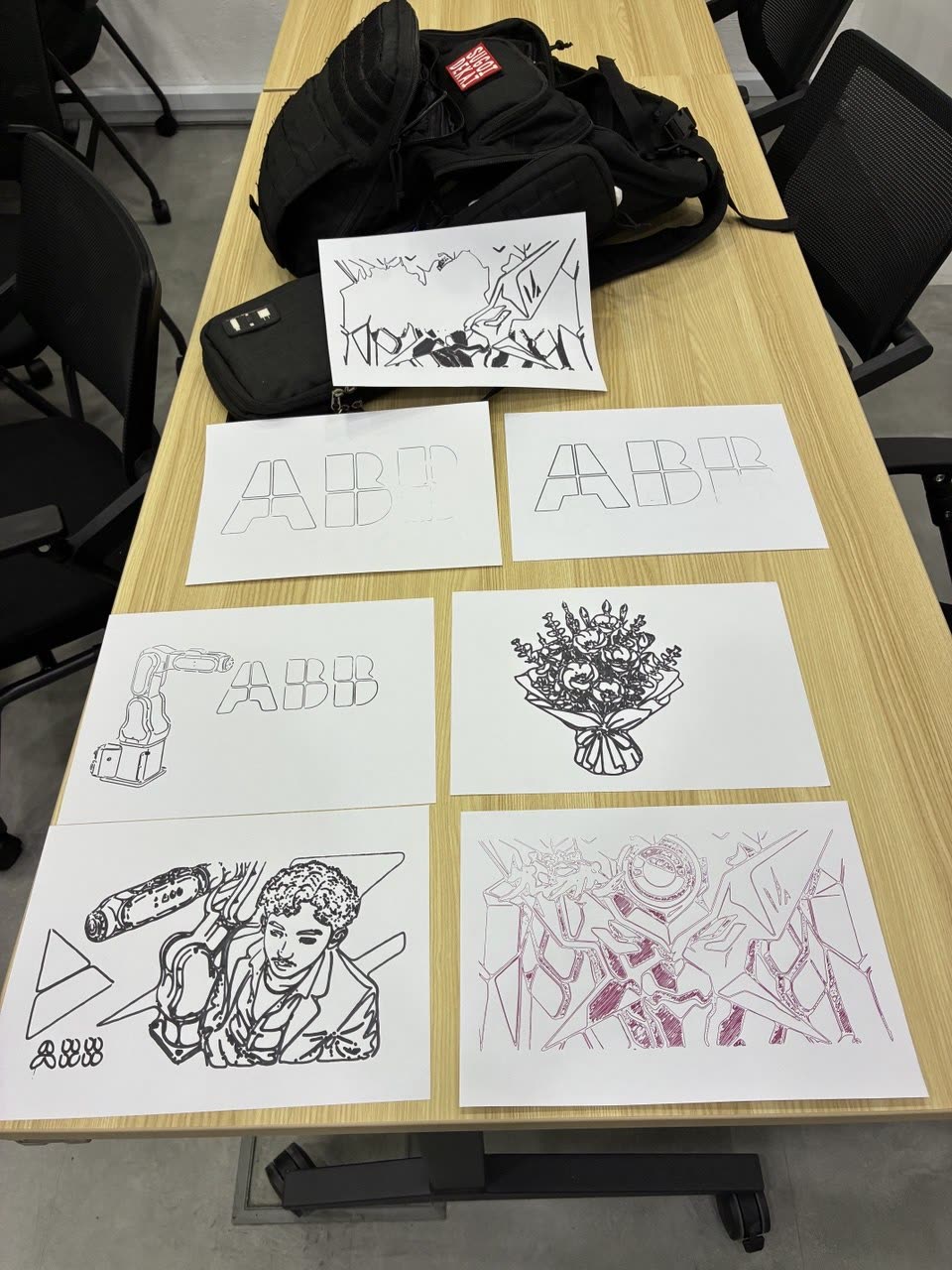 Seven finished RobotDraw drawings laid out on a desk